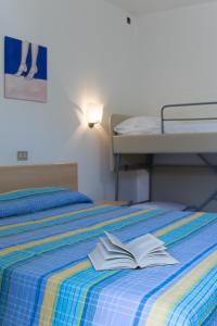 Una cama con un libro abierto encima. en Hotel Elvia en Lignano Sabbiadoro