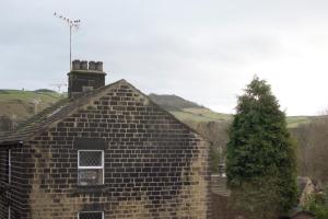 una vieja casa de ladrillo con una chimenea y un árbol en The Blacksmiths Arms en Penistone