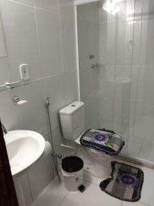 Baño blanco con aseo y lavamanos en Apartamento Temporada Cabo Frio, en Cabo Frío