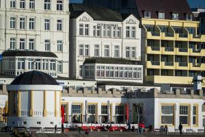 eine Gruppe von Gebäuden mit Leuten, die vor ihnen laufen in der Unterkunft Strandhotel Ostfriesenhof in Borkum