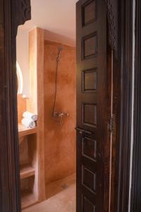 La salle de bains est pourvue d'une douche et d'une porte. dans l'établissement Riad 46, à Marrakech