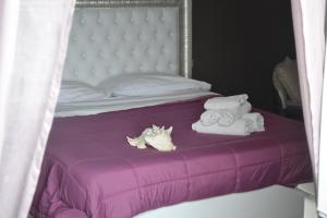 Una cama con sábanas moradas y toallas. en Terra Murata Boutique b&b, en Procida