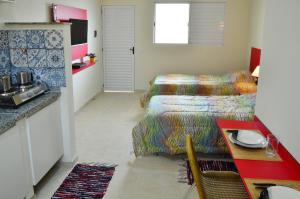 a room with two beds and a table and a kitchen at Studio Ana Laura in São Paulo