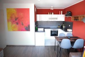 een keuken met rode muren en een tafel en stoelen bij Apartment von Betzenstein in Markkleeberg
