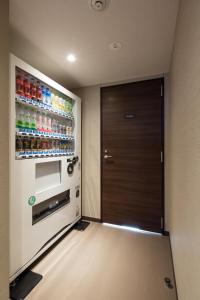 een kamer met een deur en een koelkast met drankjes bij New Matto Terminal Hotel in Hakusan