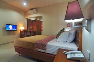 a hotel room with a bed and a desk with a phone at Taman Ayu Town House in Denpasar