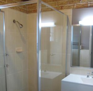 a bathroom with a shower and a toilet and a sink at Beenleigh Village Motel in Beenleigh