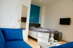 a living room with a blue couch and a bed at Deichhotel Rose in Juist