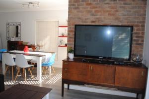 uma sala de estar com uma grande televisão de ecrã plano numa cómoda de madeira em Villa in the Village em Joanesburgo