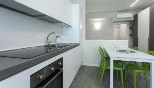 een keuken met een wastafel en een tafel met groene stoelen bij Italianway-Cadorna 10B in Milaan