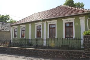 una pequeña casa verde y blanca con una valla en Homoky Pincészet és Vendégház, en Tállya