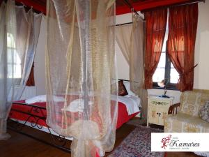 a bedroom with a bed with curtains and a chair at Hotel Kamares in Tsepelovo