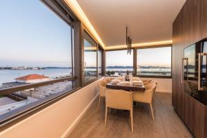 jadalnia ze stołem i krzesłami oraz dużymi oknami w obiekcie Luxury Apartment Kortina w mieście Zadar