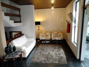 a living room with a white couch and two chairs at Del Rey Hotel in Barbacena
