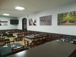 a dining room with tables and chairs and pictures on the wall at Pension Grilo in Padrón