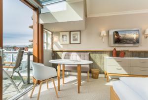ein Wohnzimmer mit einem Tisch und einem Balkon in der Unterkunft Hotel Meersinn klimaneutral in Binz