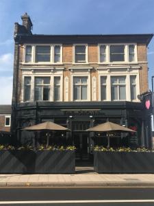 un bâtiment avec deux parasols devant lui dans l'établissement PubLove @ The Crown, Battersea, à Londres