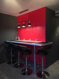 - un bar dans une pièce dotée d'un mur rouge dans l'établissement Au Studi'Ô, à Saint-Bonnet-en-Champsaur