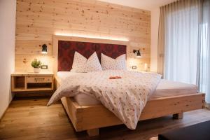 a bedroom with a large bed with a wooden wall at Alpine Chalets App. Pichlerhof in Brunico
