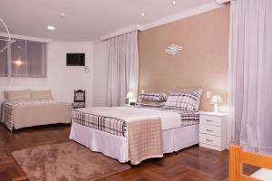 a bedroom with two beds and a tv in it at Hospedaria Casa Real in Santa Cruz de Minas