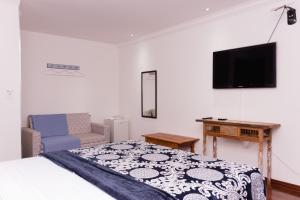 a bedroom with a bed and a flat screen tv at Hospedaria Casa Real in Santa Cruz de Minas