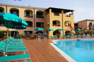 a hotel with chairs and umbrellas next to a swimming pool at Nicolaus Club Torre Moresca in Cala Liberotto