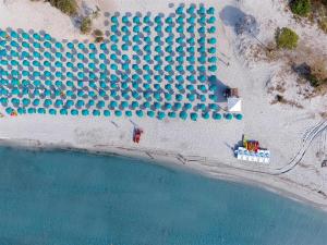 eine Luftansicht auf einen Strand mit einer Gruppe von Sonnenschirmen in der Unterkunft Nicolaus Club Torre Moresca in Cala Liberotto