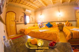 a room with two beds and a table with fruit on it at Hotel Babylon Dades in Imdiazene