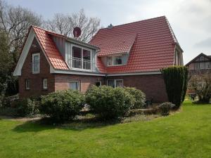 uma casa com um telhado vermelho e alguns arbustos em Pension-Marion em Bad Zwischenahn