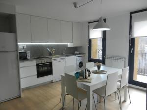 a kitchen with a white table and white cabinets at Ca de Géraldine in El Pont de Suert