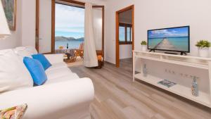 een woonkamer met een witte bank en een tv bij Sa Marina / Sa Marina 7A in Alcudia