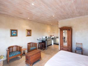 a bedroom with a bed and chairs and a kitchen at River Cottage in Kenton on Sea
