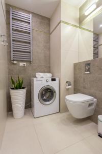 a bathroom with a washing machine and a toilet at Millennium Awangarda Green in Warsaw