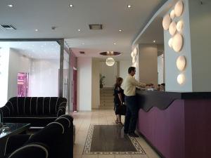 a man and a woman standing at a counter in a restaurant at Hotel Astron in Kardítsa