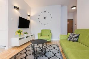 a living room with a couch and a clock on the wall at Millennium Awangarda Green in Warsaw