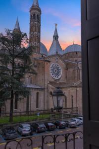 uma igreja com uma torre de relógio e carros estacionados num parque de estacionamento em Hotel Casa Del Pellegrino em Pádua