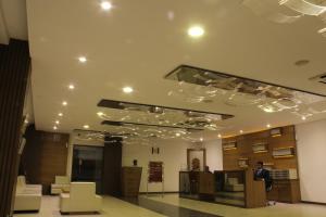 a man is standing in a lobby with a ceiling with lights at Hotel Platinum Inn in Ahmedabad