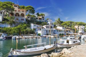 un gruppo di imbarcazioni ormeggiate in un porto con edifici di Can Molino a Cala Santanyi