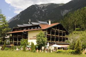 un grand bâtiment avec une montagne en arrière-plan dans l'établissement Geniesserhotel Alpin GmbH, à Achenkirch