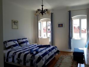 a bedroom with a blue and white bed and two windows at Piazza Old Town Apartment in Split