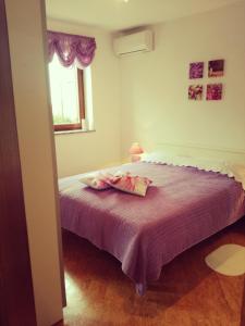 ein Schlafzimmer mit einem Bett mit violetter Bettwäsche und einem Fenster in der Unterkunft Room Kris with private entrance & private bathroom in Umag