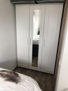 1 dormitorio con armarios blancos y 1 cama con espejo en Ferienwohnung Anke - Apartment 5d, en Heinsberg