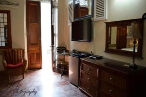 a living room with a television and a dresser with a mirror at Boutique Hotel Belgica in Ponce