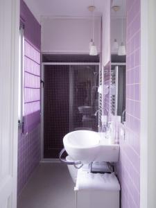 bagno con lavandino bianco e piastrelle viola di B&B Ricci a Livorno