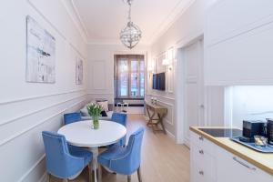 a kitchen and dining room with a white table and blue chairs at JP Sopot Apartamenty in Sopot