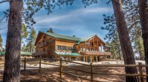 a log home in the woods with a fence at Elktrace Bed and Breakfast in Pagosa Springs
