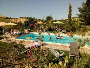 a swimming pool with chairs and umbrellas and people in it at Agriturismo Cignale della Società Agricola Cignale srl in Penne