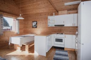 a kitchen with white appliances and a wooden wall at Grandane Feriehus in Stongfjorden