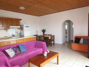 sala de estar con sofá púrpura y cocina en All Seasons House, en Liridhianá