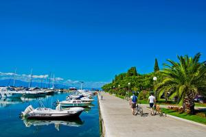 people walking along a sidewalk next to a marina with boats at Apartment Luna in Malinska